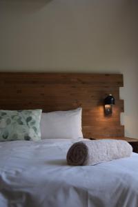 a white bed with a wooden headboard and a pillow at Hyena Den - Marloth Park in Marloth Park