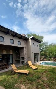 a house with two chairs and a swimming pool at Hyena Den - Marloth Park in Marloth Park