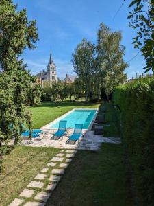 a swimming pool with lounge chairs and a church at Les Ifs en Sologne avec piscine: Château & Beauval in Millançay