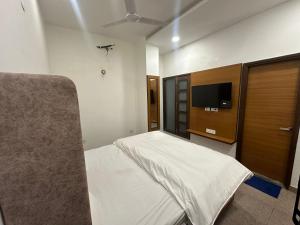 een slaapkamer met een bed en een flatscreen-tv bij The Maduka in Chandīgarh