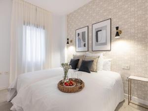 Una cama blanca con una cesta de fruta. en Central Stylish and Elegant 1 & 2 BR apartments I en Granada