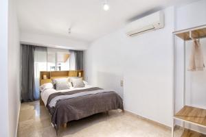 een slaapkamer met een bed in een witte kamer bij Bibrambla penthouse over Cathedral in Granada