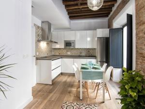 グラナダにあるChezmoihomes Central Ethnic style apartmentの白いキャビネット、テーブルと椅子付きのキッチンが備わります。