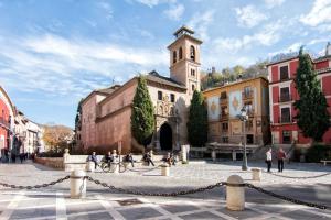 a group of people walking around a building with a clock tower at CMH Alhambra Dreams - Luxury & Romantic Hideaway in Granada