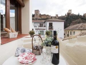 Chezmoihomes Alhambra Penthouse في غرناطة: زجاجة من النبيذ موضوعة على طاولة على شرفة