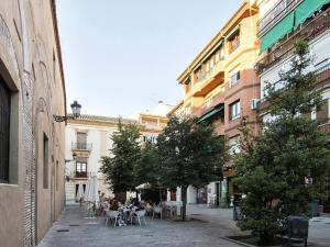 eine Stadtstraße mit Tischen, Stühlen und Gebäuden in der Unterkunft Chezmoihomes Premium Loft private terrace in Granada