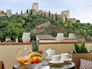 a table with a bowl of fruit with a castle in the background at Chezmoihomes Alhambra Penthouse 2 private terraces in Granada