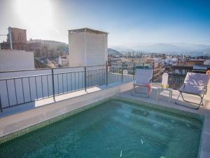 balcón con piscina y 2 sillas en Trinidad Deluxe 1, en Granada