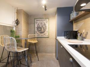 a kitchen with a counter and stools in it at Chezmoihomes Cathedral Apartment in Granada