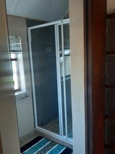 una puerta de ducha de cristal en un baño con ventana en triple S guest house, en Ciudad del Cabo