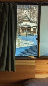 a window with a view of a snow covered yard at Yukiumi Furano in Furano