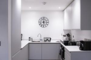 a kitchen with white cabinets and a clock on the wall at Luxury Mcr 2bed,2bath Apartment- Central location! in Manchester +28 photos