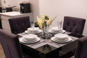 einem Esstisch mit Tellern und einer Vase aus Blumen in der Unterkunft Luxury Stay 5 mins to Manchester city centre! in Manchester