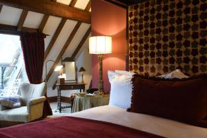 um quarto com uma cama com um candeeiro e uma cadeira em The Priory Hotel em Wareham