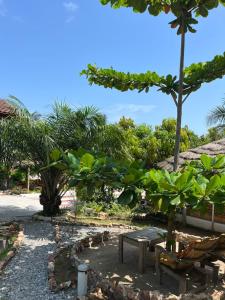 a park with a bench and a table and trees at African Treasure Beach Resort in Kokrobite