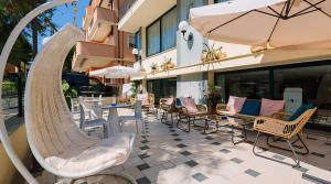 un patio al aire libre con sillas, mesas y una sombrilla en Hotel Baltic, en Misano Adriatico