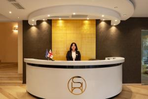 a woman standing behind a counter in a lobby at Sephia Hotel in Tbilisi City