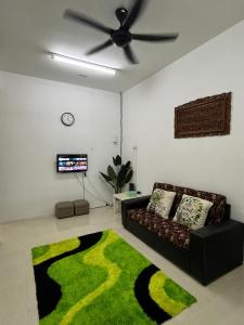 ein Wohnzimmer mit einem Sofa und einem grünen Teppich in der Unterkunft Sutera Cottage, Best Place for Your Short Getaway in Sungai Petani