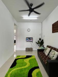 ein Wohnzimmer mit einem Sofa und einem Deckenventilator in der Unterkunft Sutera Cottage, Best Place for Your Short Getaway in Sungai Petani