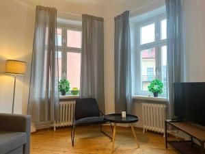 a living room with a chair and a table and two windows at Stay Inn Apartments Norrmalm in Stockholm