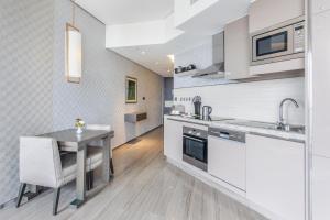 een keuken met witte kasten en een tafel met een stoel bij Spacious Studio Apartment in Hyatt Regency Dubai Creek Heights by the S Holiday Homes in Dubai
