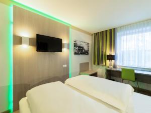 a hotel room with a bed and a desk and a tv at B&B HOTEL Bochum-Hbf in Bochum