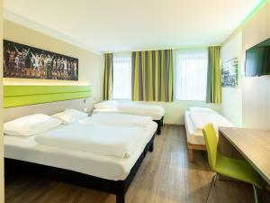 una camera d'albergo con tre letti e un tavolo di B&B HOTEL Bochum-Hbf a Bochum