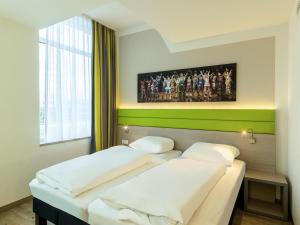 two beds in a room with a painting on the wall at B&B HOTEL Bochum-Hbf in Bochum