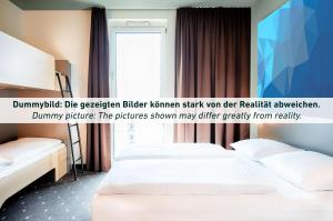 B&B HOTEL Magdeburg-Barleben في بارليبين: غرفة فندقية بسريرين ونافذة