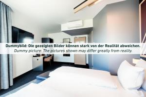 a bedroom with a bed and a sign that reads dummydbdbiger blitzer at B&B HOTEL Kassel-Industriepark in Kassel