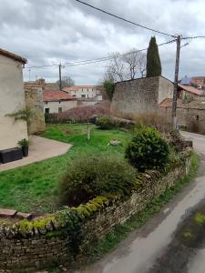 a garden with a stone wall and some bushes at Le petit Migault in La Creche