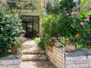 a garden with flowers and plants in front of a building at Annie's Boutique Apartment in Jerusalem in Jerusalem