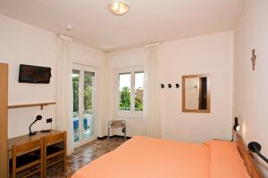 a bedroom with an orange bed and a desk and windows at Hotel Garden in Alassio