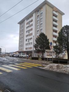 duży biały budynek z samochodami zaparkowanymi na parkingu w obiekcie Joli Studio w mieście La Chaux-de-Fonds