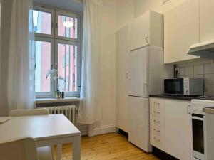 Biała kuchnia ze stołem i kuchenką mikrofalową w obiekcie Stay Inn Apartments Norrmalm w Sztokholmie