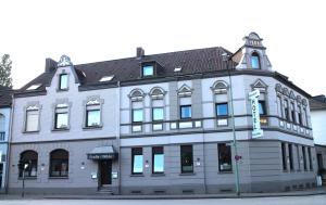 un grand bâtiment gris au coin d'une rue dans l'établissement Hotel-Restaurant Große-Wilde, à Bottrop
