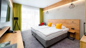 - une chambre avec un grand lit et des oreillers jaunes dans l'établissement Czarna Perła - Czarna Góra Resort by Sun & Snow z nielimitowanym basenem, à Sienna