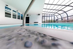an indoor swimming pool with a swimming pooliteratoriteratorachuachuythonythonythonython at Kyriad Prestige Residence & Spa Cabourg-Dives-sur-Mer in Dives-sur-Mer