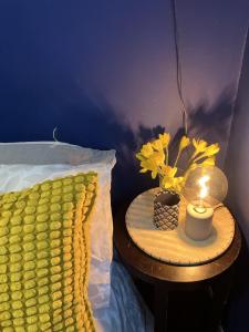 a table with a lamp and yellow flowers on a bed at 3 bedroom house in Bedminster near Wapping Wharf in Bristol