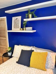 a blue wall with shelves above a bed at 3 bedroom house in Bedminster near Wapping Wharf in Bristol