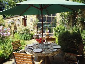 un tavolo con ombrellone verde in giardino di Wonderful Picturesque Countryside Cottage a Bloxham