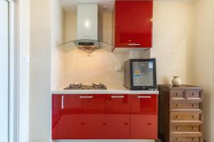 cocina roja con fogones y microondas en Dalian Baobab Apartment en Dalian