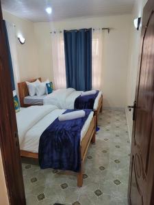 two beds in a hotel room with blue curtains at Gloria House in Nairobi