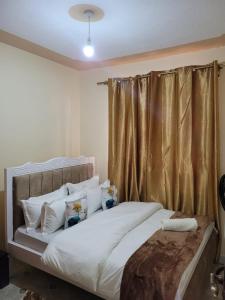 1 dormitorio con 1 cama con sábanas y almohadas blancas en Gloria House en Nairobi