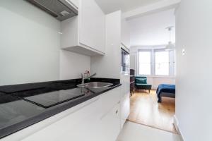 een keuken met witte kasten en een wastafel bij Cannon Street Studios in Londen
