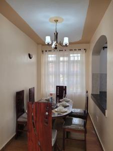 uma sala de jantar com uma mesa e cadeiras e um lustre em Gloria House em Nairobi