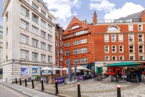 um grupo de edifícios com mesas e guarda-sóis numa rua em Cannon Street Studios em Londres