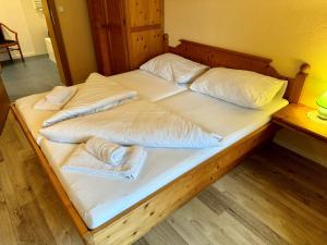 een groot bed met witte lakens en kussens erop bij Familienurlaub mit Baden & Berge, FeWo 2 in Thiersee