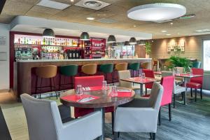 un restaurant avec des tables et des chaises ainsi qu'un bar dans l'établissement Campanile Villennes-Sur-Seine - Poissy - Hôtel rénové en 2024, à Villennes-sur-Seine