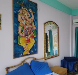 a painting on the wall next to a mirror at Casa di Mara in Puttaparthi